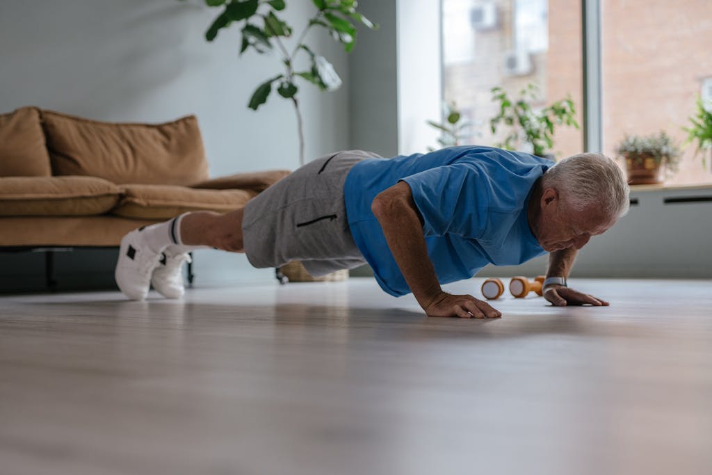 Senior man doing push-ups at home, focusing on fitness and healthy lifestyle.